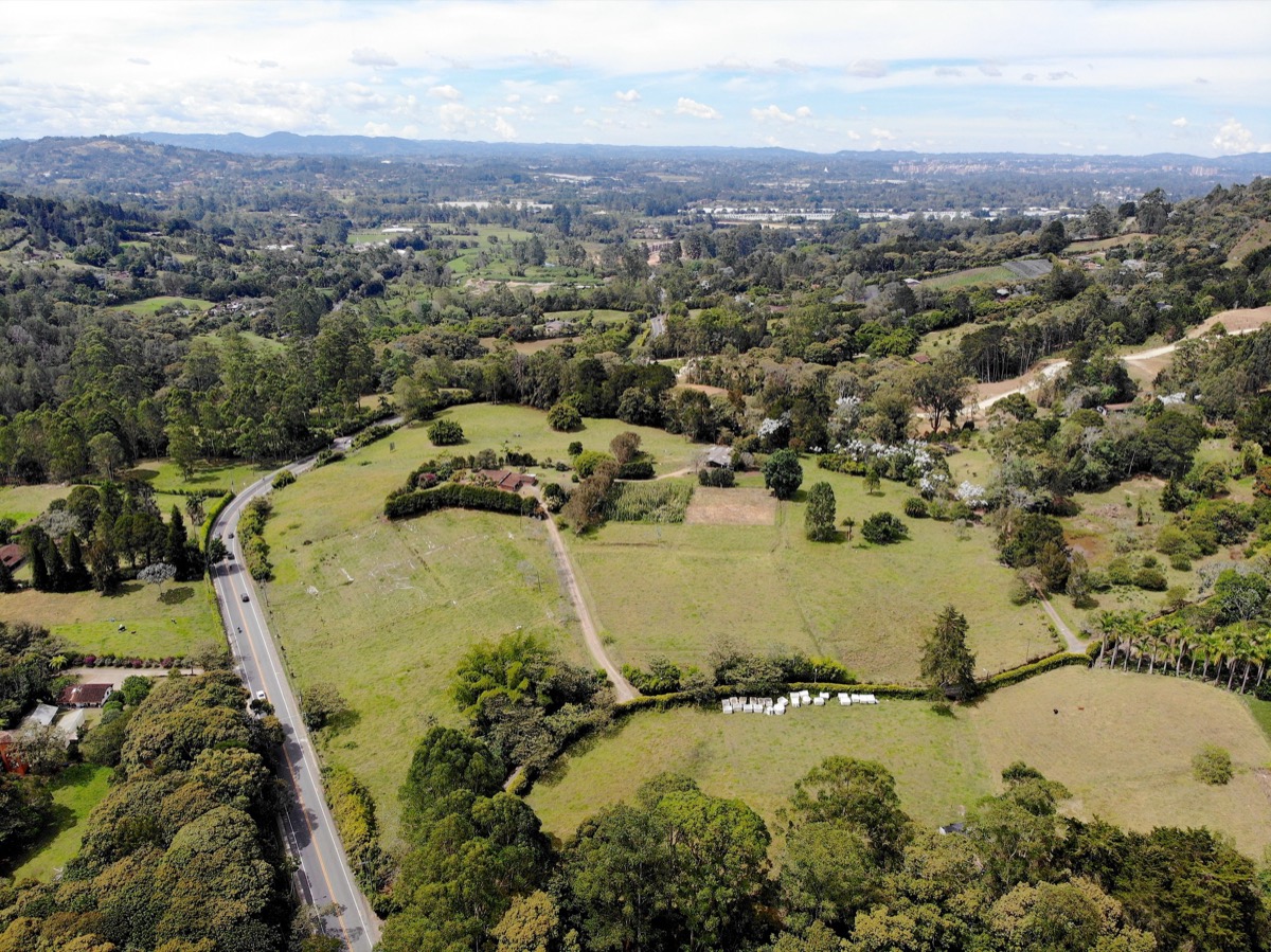 Vista aérea de la vía a Llanogrande, con fincas, bosque y montañas en el horizonte